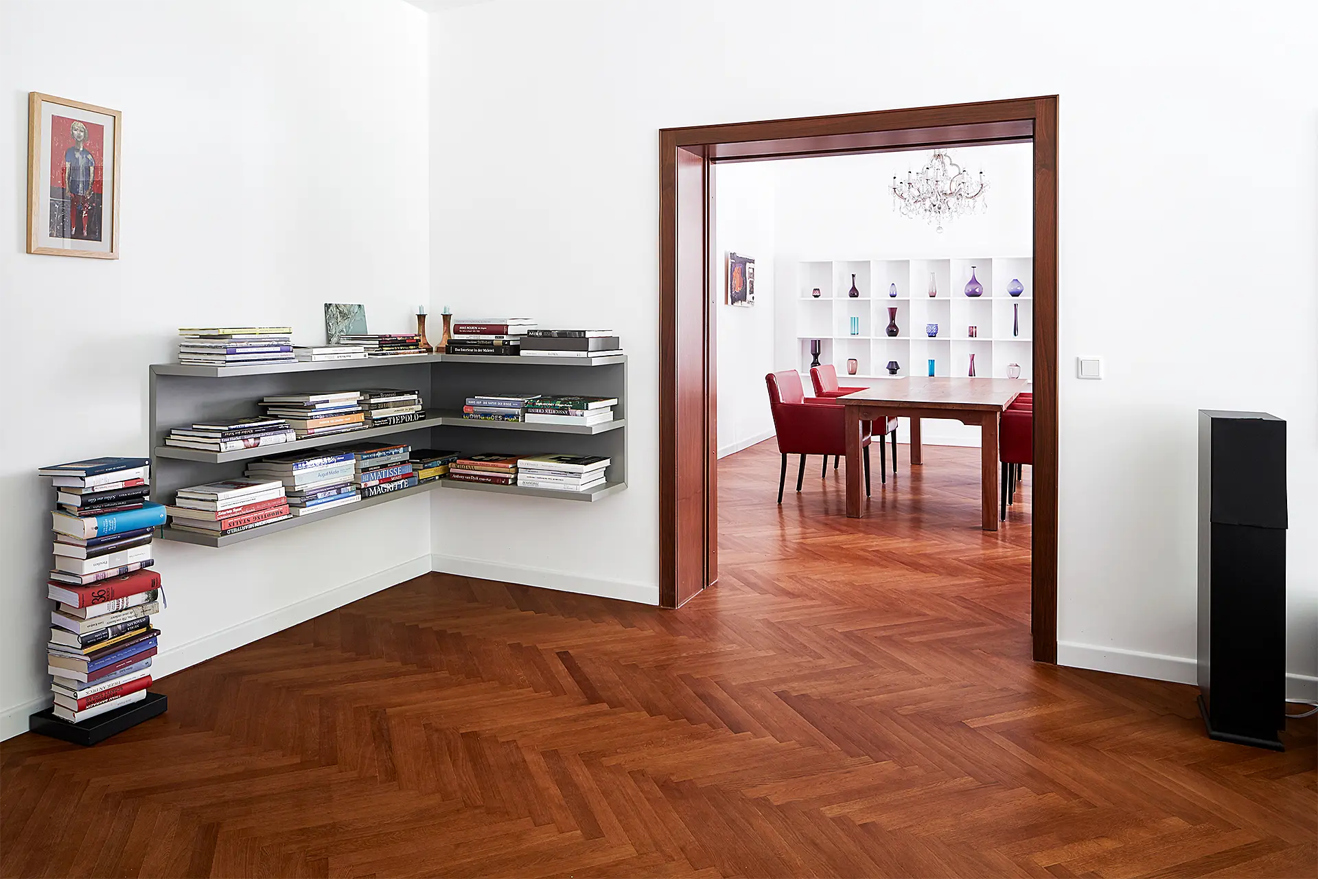 Ein graues freischwebendes Eckregal an einer weißen Wand ist mit Büchern befüllt.