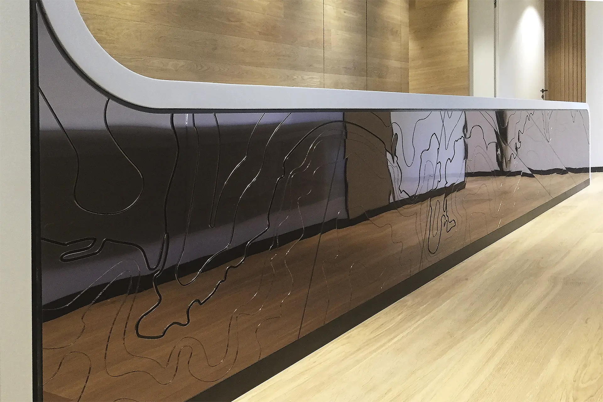 Blick auf einen Ausschnitt der glänzenden Vorderseite eines Empfangstresen. Dieser ist aus Mineralwerkstoff.