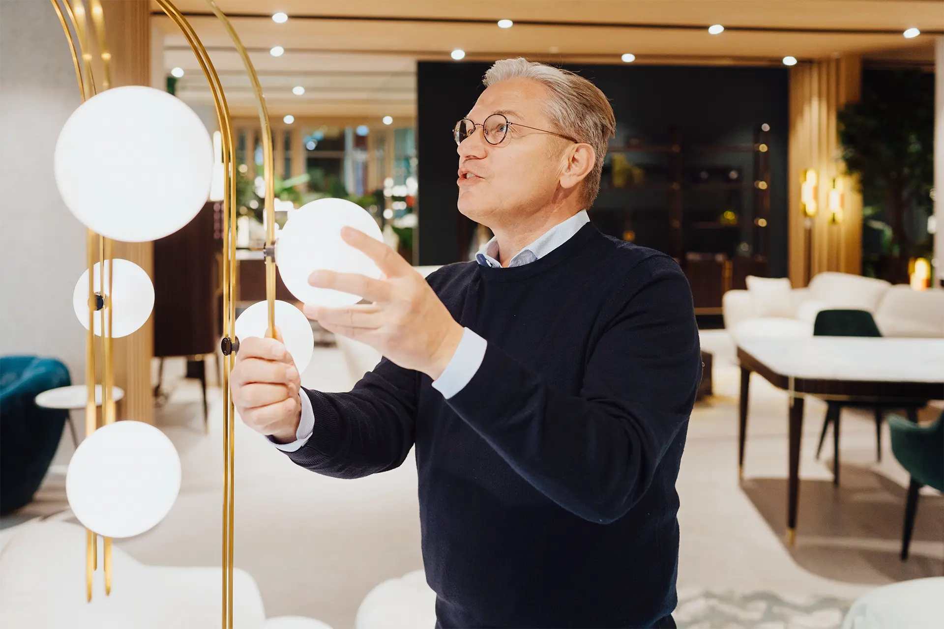 Ulrich Weinkath steht in einem Interior-Showroom am Neuen Wall. Er begutachtet eine Stehlampe mit kreisrunden Lampenschirmen aus Glas.