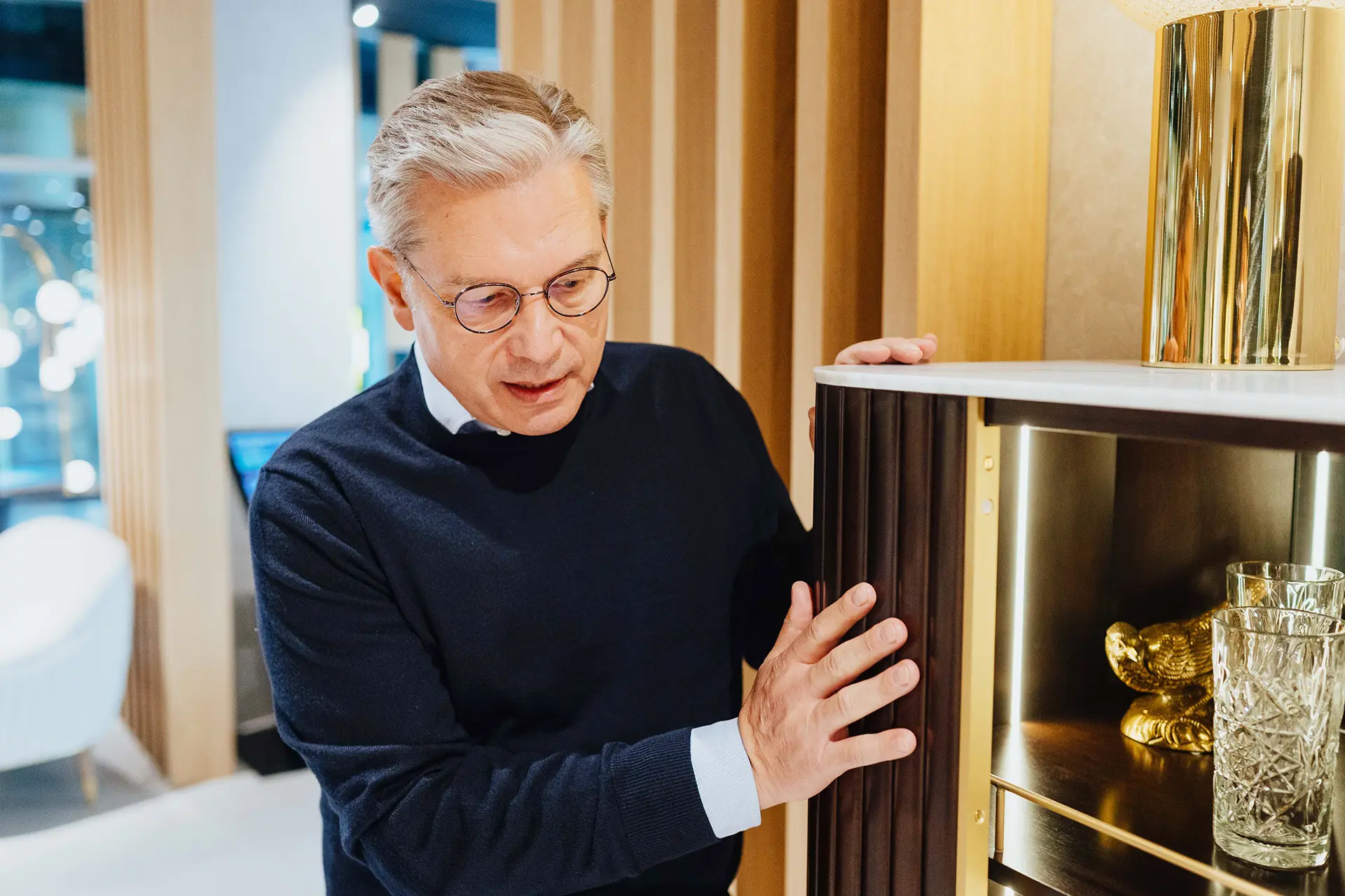 Ulrich Weinkath begutachtet einen Schrank aus Holz in einem Interior-Showroom am Neuen Wall. Er scheint zu sprechen.